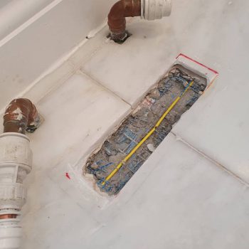 Under tile heating repair with yellow wire in cut out hole